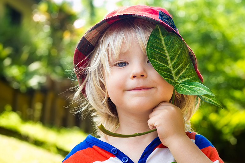 A child with a leaf covering part of his face