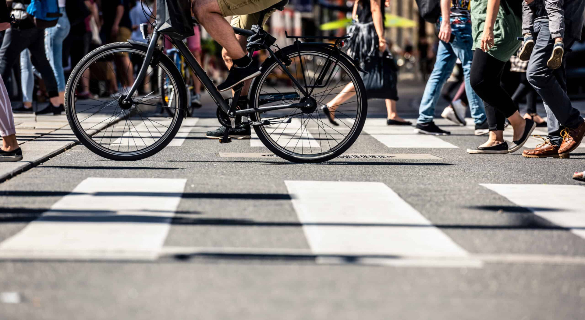 The cyclist passing the pedestrian cross among the other pedestrians
